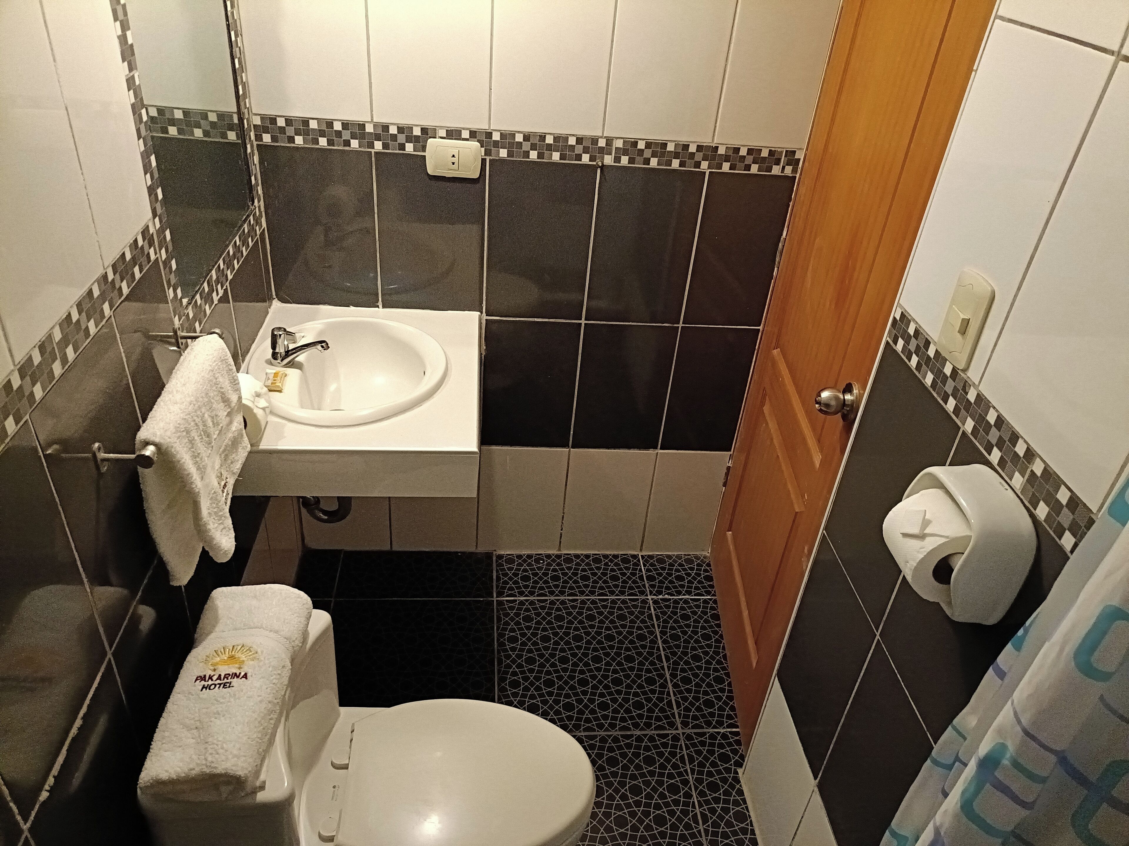 Ein kleines Badezimmer mit Waschbecken, Toilette und einem Handtuchhalter mit Handtuch.