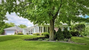 A two-story house with a large tree in front, a well-maintained lawn, and a garage. - La Maison du Bonheur 🫶 (Saint-Paul-d'Abbotsford)