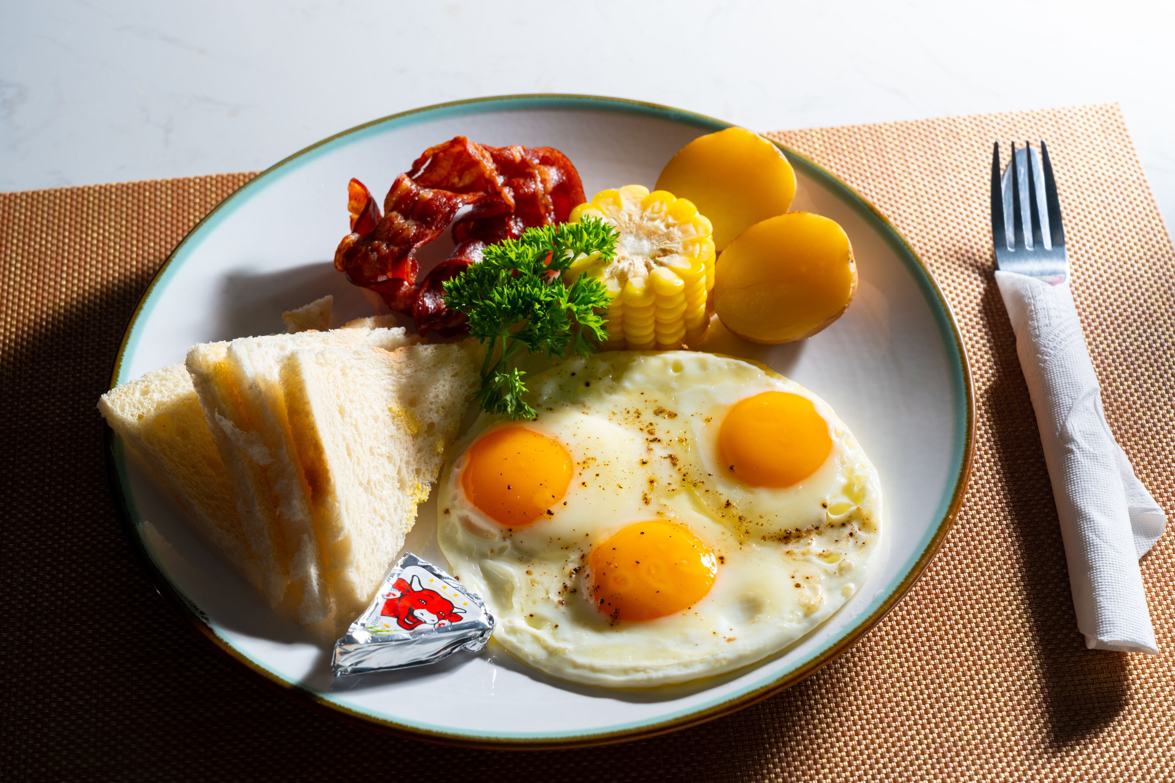 A plate with eggs, corn, bacon, and toast.