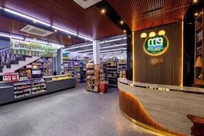 A modern retail store interior with a curved counter, shelves stocked with various products, and a prominent logo on the wall.