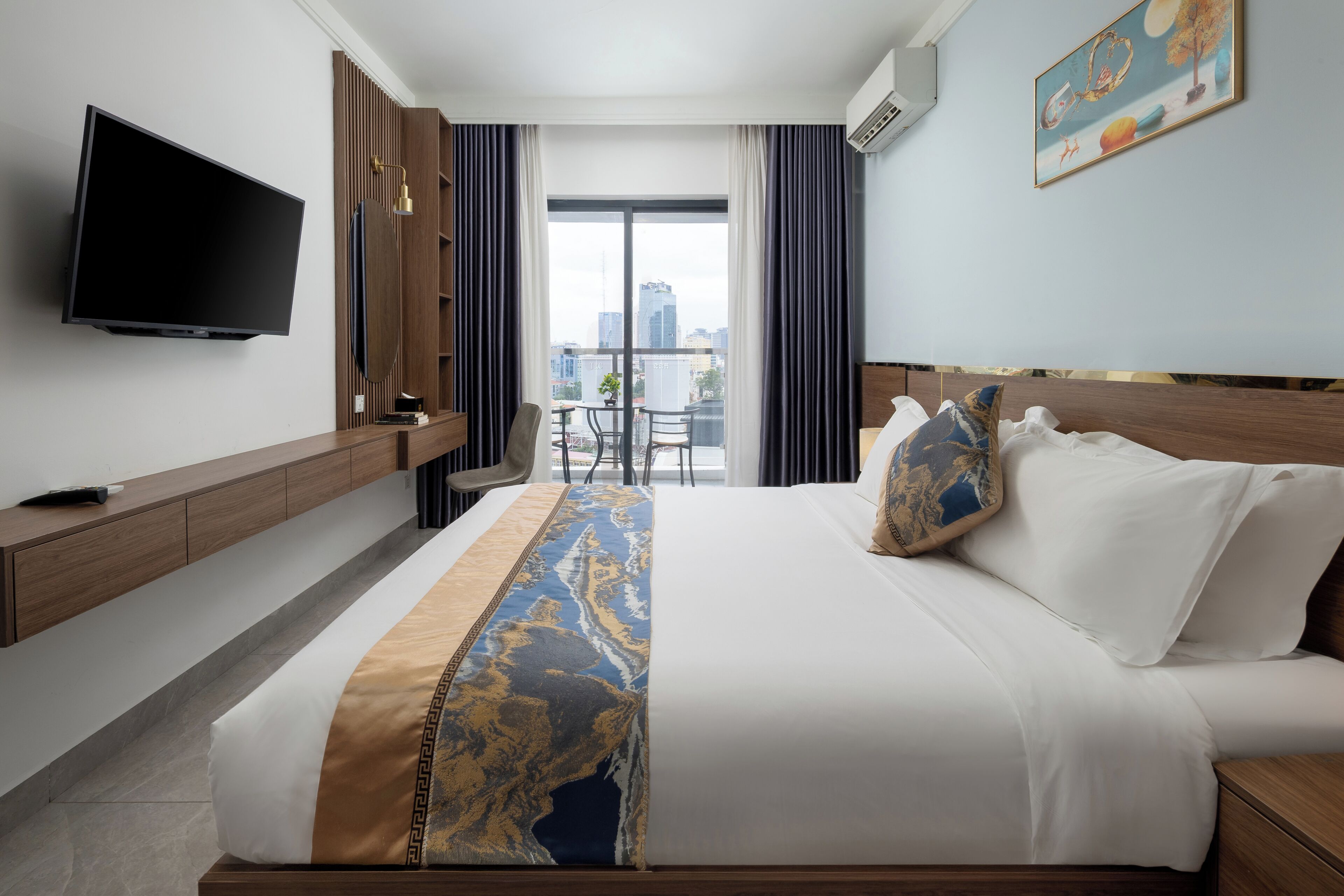 A hotel room with a bed, a TV, a desk, and a view of the city.