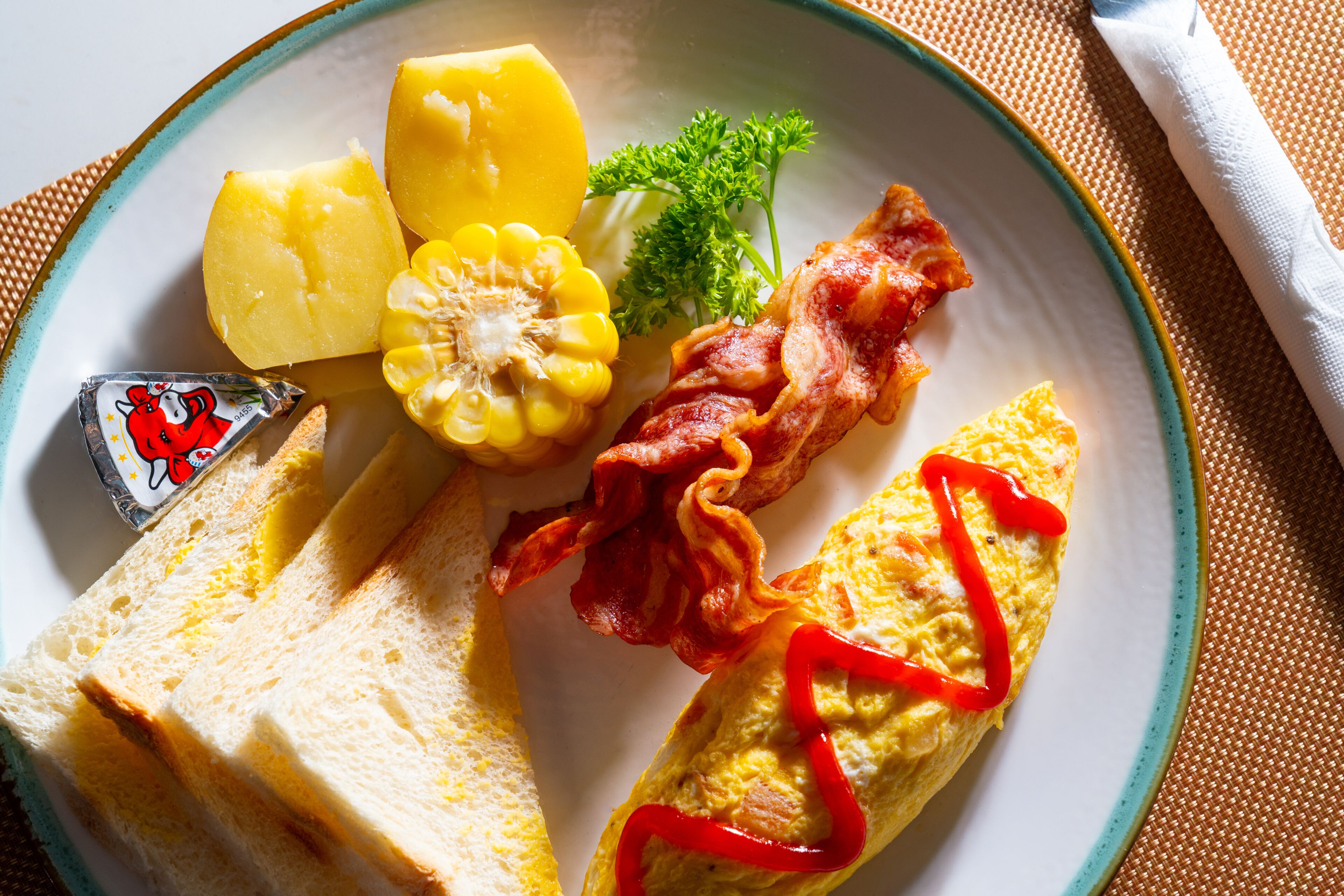 A plate with eggs, bacon, potatoes, corn, and toast.