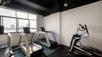 A gym with treadmills, a stationary bike, and a bench.