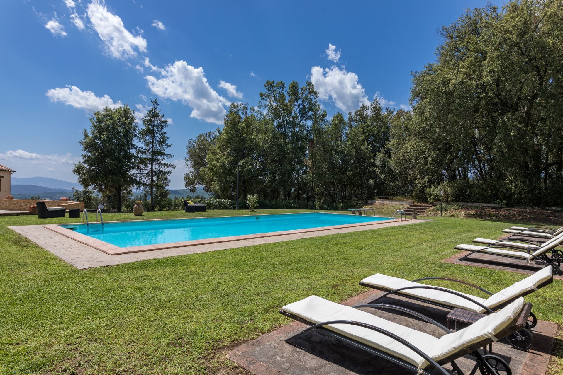 Ein Pool mit Liegestühlen und Blick auf Bäume und Berge.