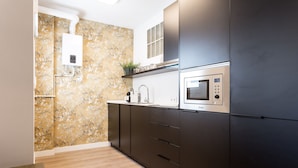 Una cocina moderna con armarios oscuros, un microondas y un calentador de agua.