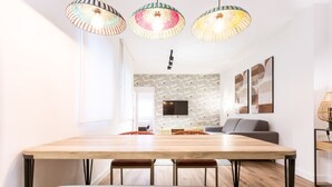 Ein moderner Essbereich mit einem Holztisch, roten und weißen Stühlen und farbenfrohen gewobenen Pendelleuchten.