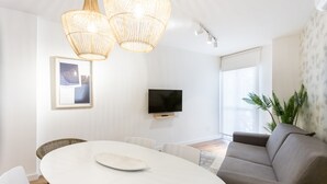 Een moderne woonkamer met een ronde eettafel, een bank en een televisie aan de muur.