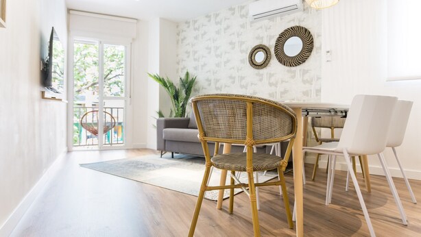 Een moderne woonkamer met een eetgedeelte, met een rieten stoel, een witte stoel en een eettafel.