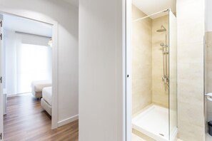 Ein modernes Badezimmer mit einer Duschkabine aus Glas, einer weißen Badewanne und Holzboden.
