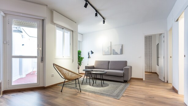Una sala de estar moderna con un sofá, una silla, una mesita y una alfombra.