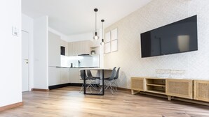Una cocina moderna con comedor, suelo de madera y un televisor de pantalla plana montado en la pared.
