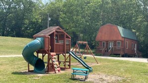 Ein Spielplatz mit Rutsche, Schaukeln und einem Picknicktisch.