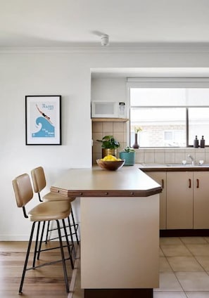 A modern kitchen with a central island, a microwave, and a window providing natural light.