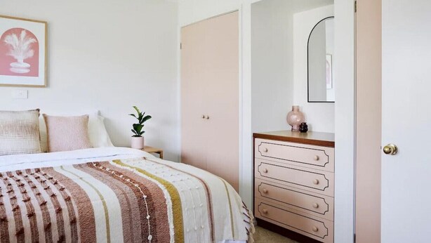 A bedroom with a bed, a dresser, a mirror, and a small plant. - Peachbud House Portarlington (Portarlington)