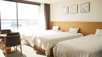 A hotel room with two beds, a desk, and a chair. There are three framed pictures on the wall.