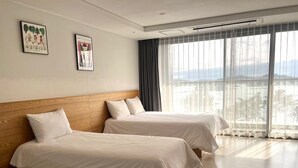 A hotel room with two beds, a large window with curtains, and artwork on the wall. - Hotel Ocean Hill (Yeosu)