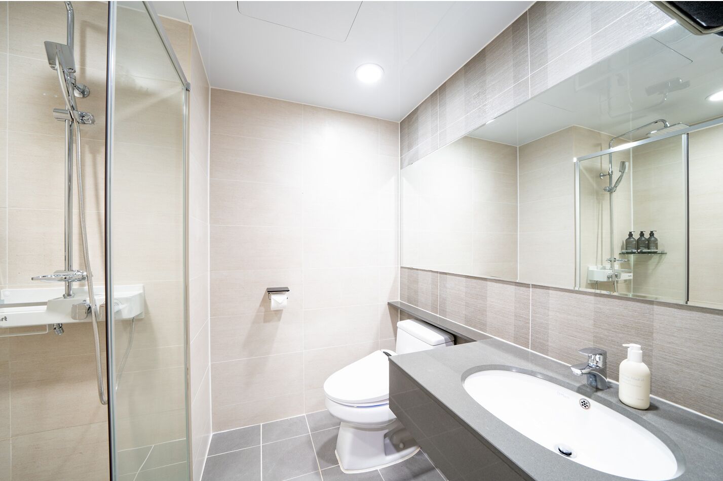 Un bagno moderno con cabina doccia in vetro, un water e un lavabo con specchio sopra.