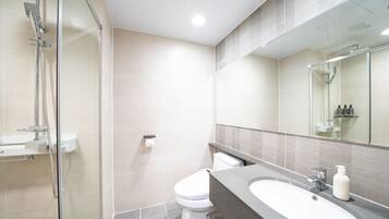 A modern bathroom with a glass shower enclosure, a toilet, and a sink with a mirror above.