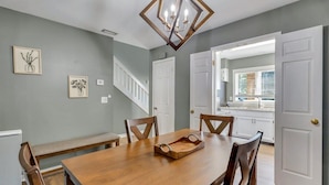 A dining area with a wooden table, chairs, and a chandelier. There are framed pictures on the wall and a staircase leading to another room. - GATA 2 -The Rustic Suite - Close to GSU (Statesboro)