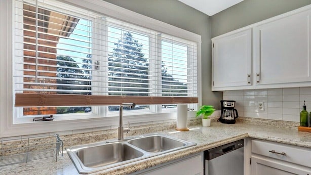 A kitchen with a double sink, white cabinets, a window with blinds, and a coffee maker. - GATA 2 -The Rustic Suite - Close to GSU (Statesboro)