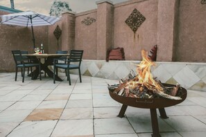 Relax and socialize in this inviting patio area with a fire pit, dining table, and comfortable seating.
