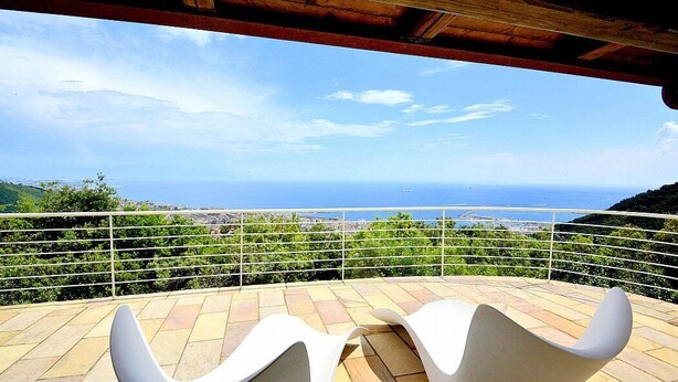 A terrace with two white chairs and a view of the sea.