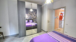 A bedroom with a bed, a wardrobe, and a mirror.