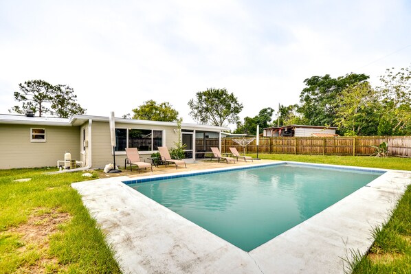 Ein Garten mit Swimmingpool, überdachter Terrasse und Holzzaun.