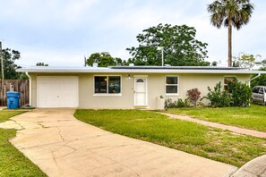 Einbungalow mit Garage, Vorgarten und einer Palme.