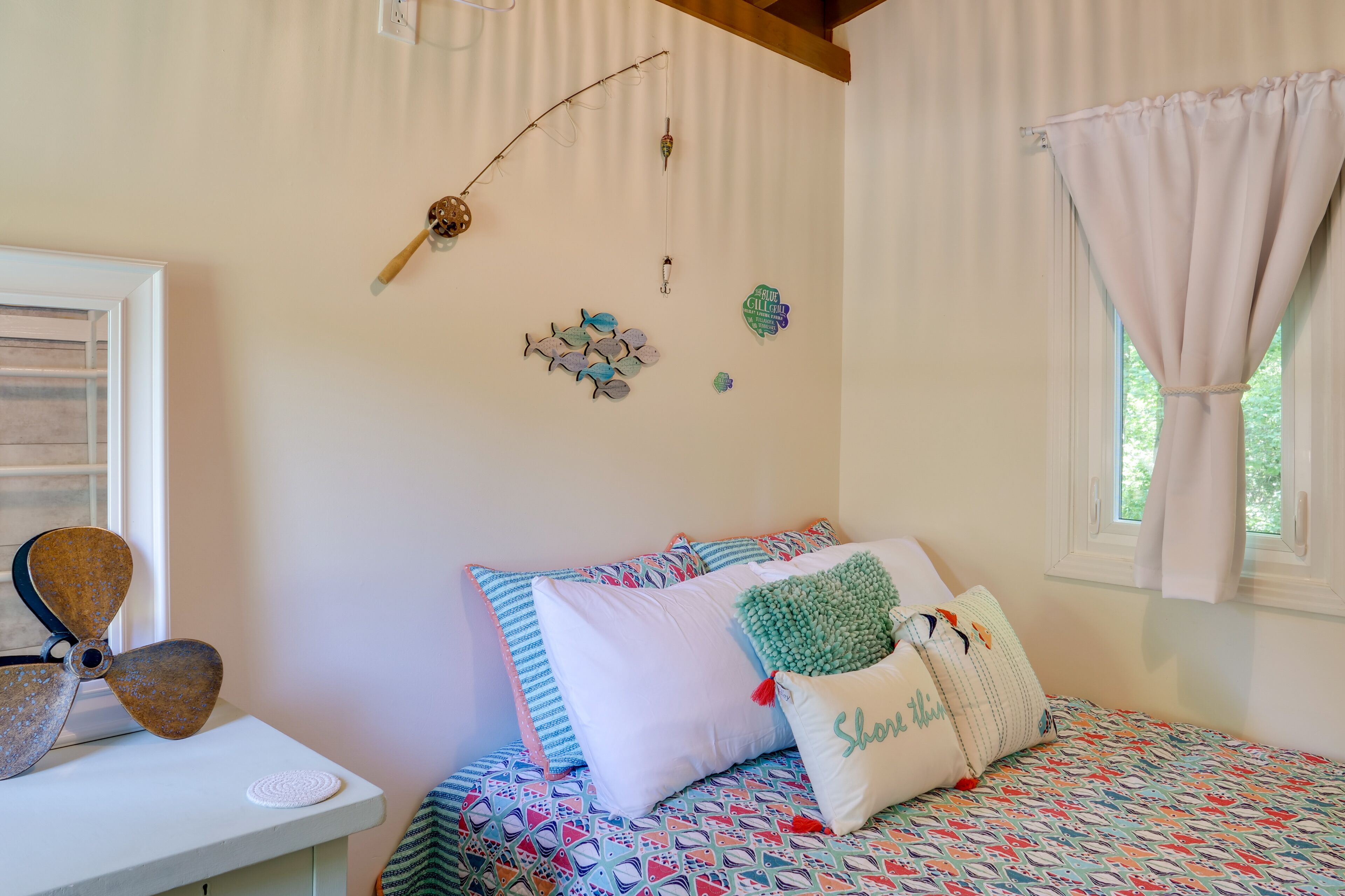 Un dormitorio con cama, almohadas, un reloj de pared y una ventana con cortinas.