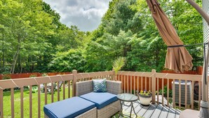 A deck with a wicker sofa, a small table, and a potted plant. - Hot Tub, Game Room & Fire Pit: Pocono Summit Home! (Pocono Summit)