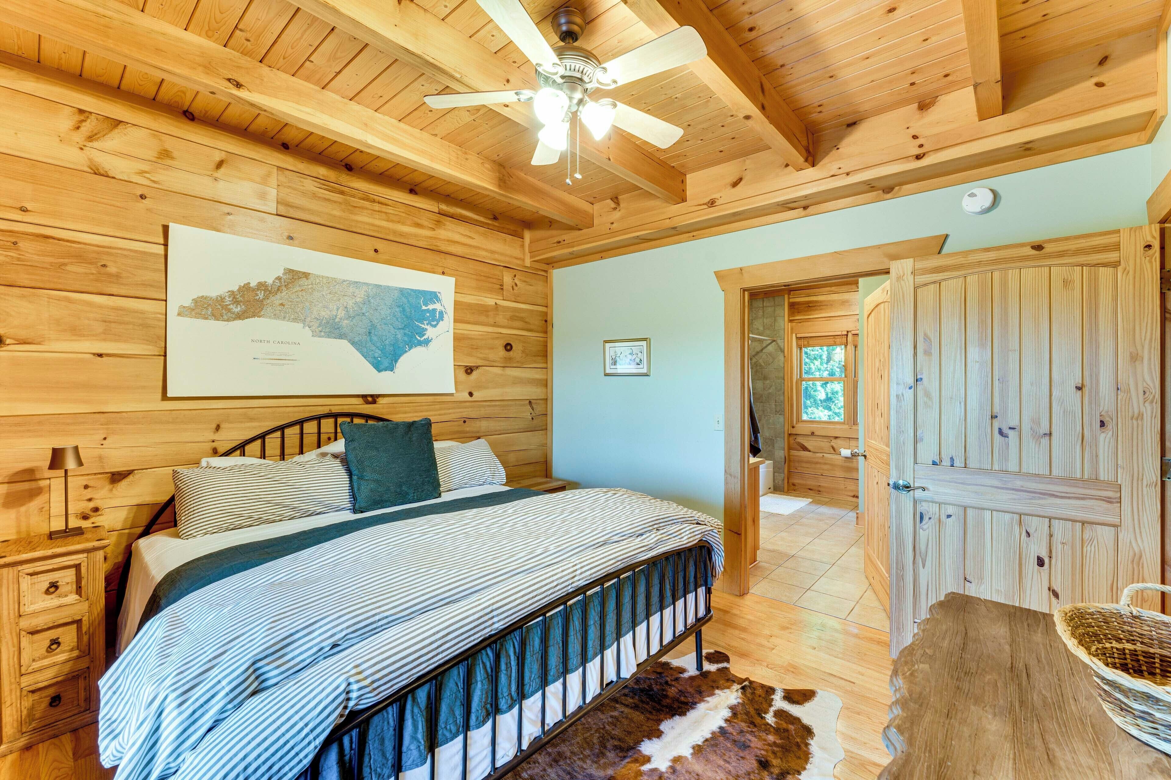 Un dormitorio de cabaña de madera con cama, ventilador de techo, un mapa en la pared y una puerta de madera.