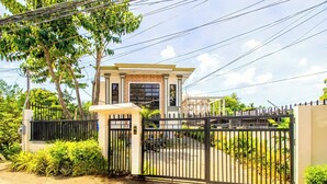 A gated residential property with a two-story house, a covered driveway, and a well-maintained garden.
