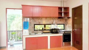A kitchen with red cabinets, a built-in microwave, a stove, and a water dispenser.