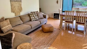Una sala de estar con sofá, reposapiés y mesa de comedor de madera con sillas.