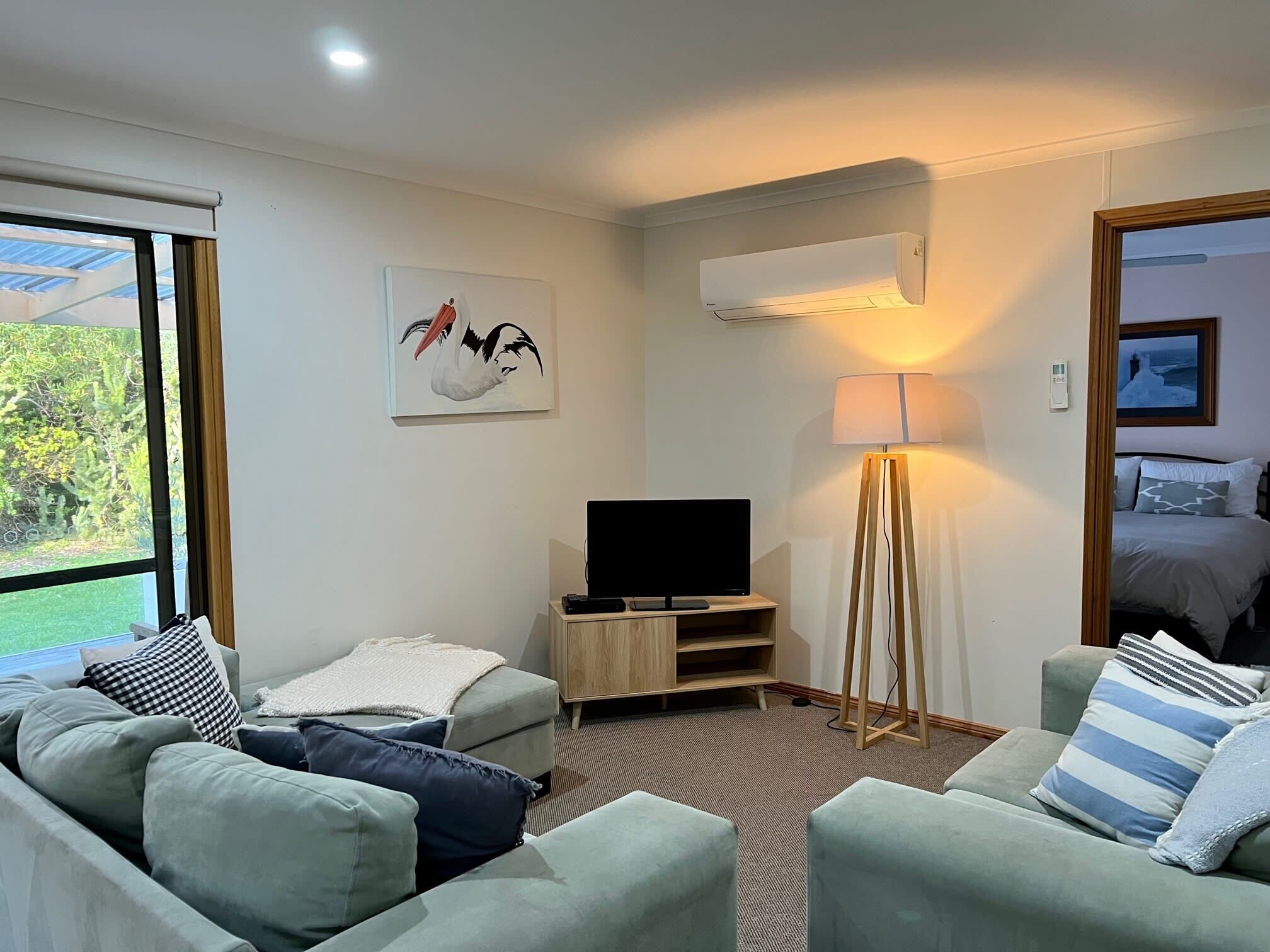 A hotel room with a sofa, a TV, a lamp, and a painting on the wall.