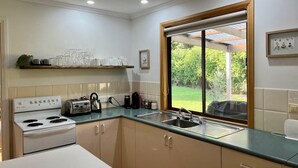 Una cocina con estufa, pileta y ventana que da a un jardín.
