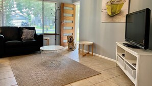 A living room with a sofa, coffee table, TV, and a dog.