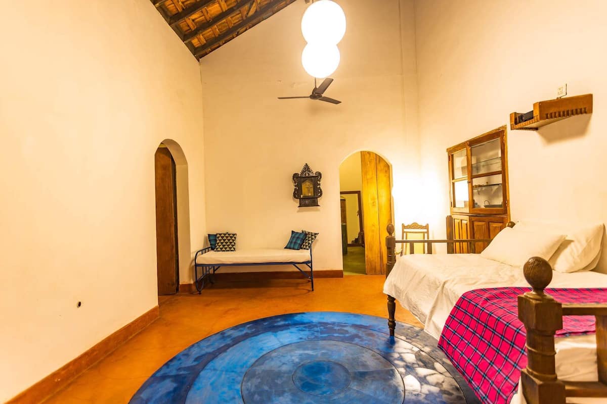 A room with a bed, a bench, a wooden cabinet, and a ceiling fan.