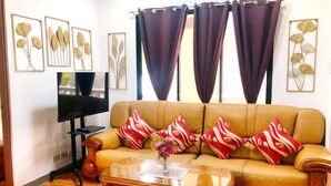 Una sala de estar con un sofá, una mesa de centro, un televisor y decoración en la pared.