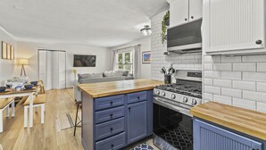 Una cocina moderna con armarios blancos, encimera de madera y estufa integrada.