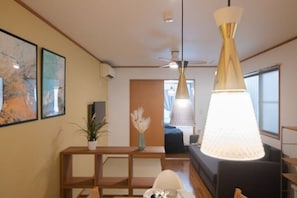 A modern living room with a sofa, a coffee table, and a hanging light fixture. - HATAGAYA Apartment 1F (Tokyo)