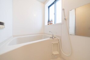 A bathroom with a bathtub, a window, and a mirror. - HATAGAYA Apartment 1F (Tokyo)