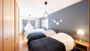 A hotel room with two beds, a bedside table with a lamp, a window with curtains, and a wall with circular decorations. - HATAGAYA Apartment 1F (Tokyo)