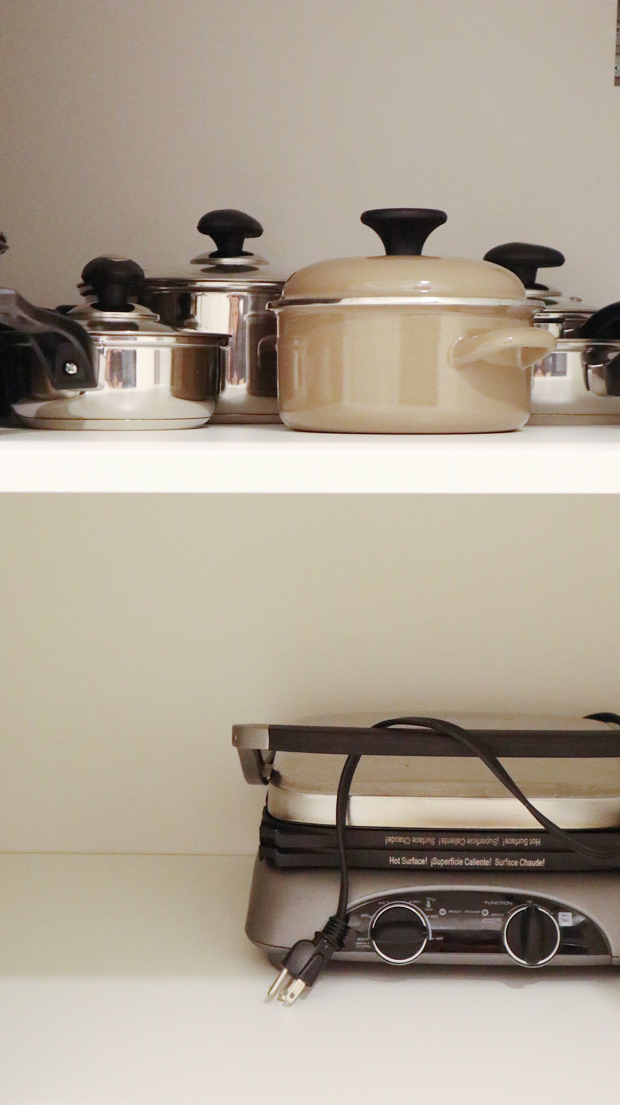 A kitchen with a stove, pots, and a slow cooker on the countertop.