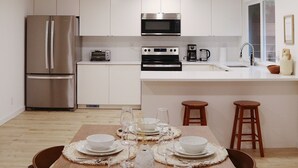 Una cocina moderna con armarios blancos, electrodomésticos de acero inoxidable y un comedor listo para una comida.