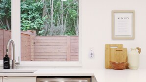 Una cocina moderna con lavavajillas integrado, una ventana con vistas a la vegetación y un menú enmarcado en la pared.