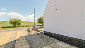 A paved pathway leading to a white building with a street lamp and a bench. - 22 Turnberry Road (Girvan)