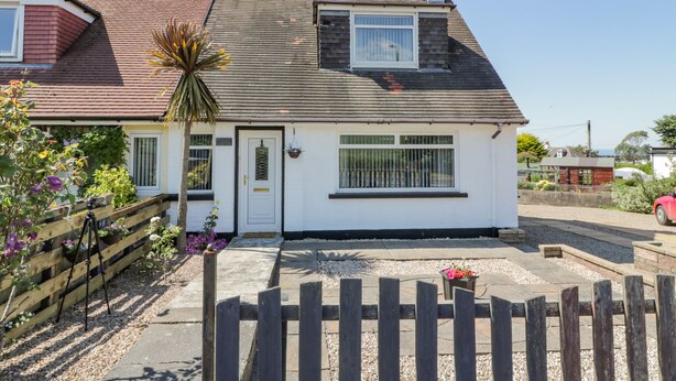A single-story house with a white exterior, a dark roof, and a small front porch. - 22 Turnberry Road (Girvan)