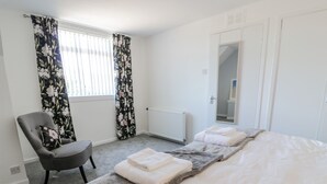 A hotel room with a bed, a chair, a radiator, and a window with curtains. - 22 Turnberry Road (Girvan)